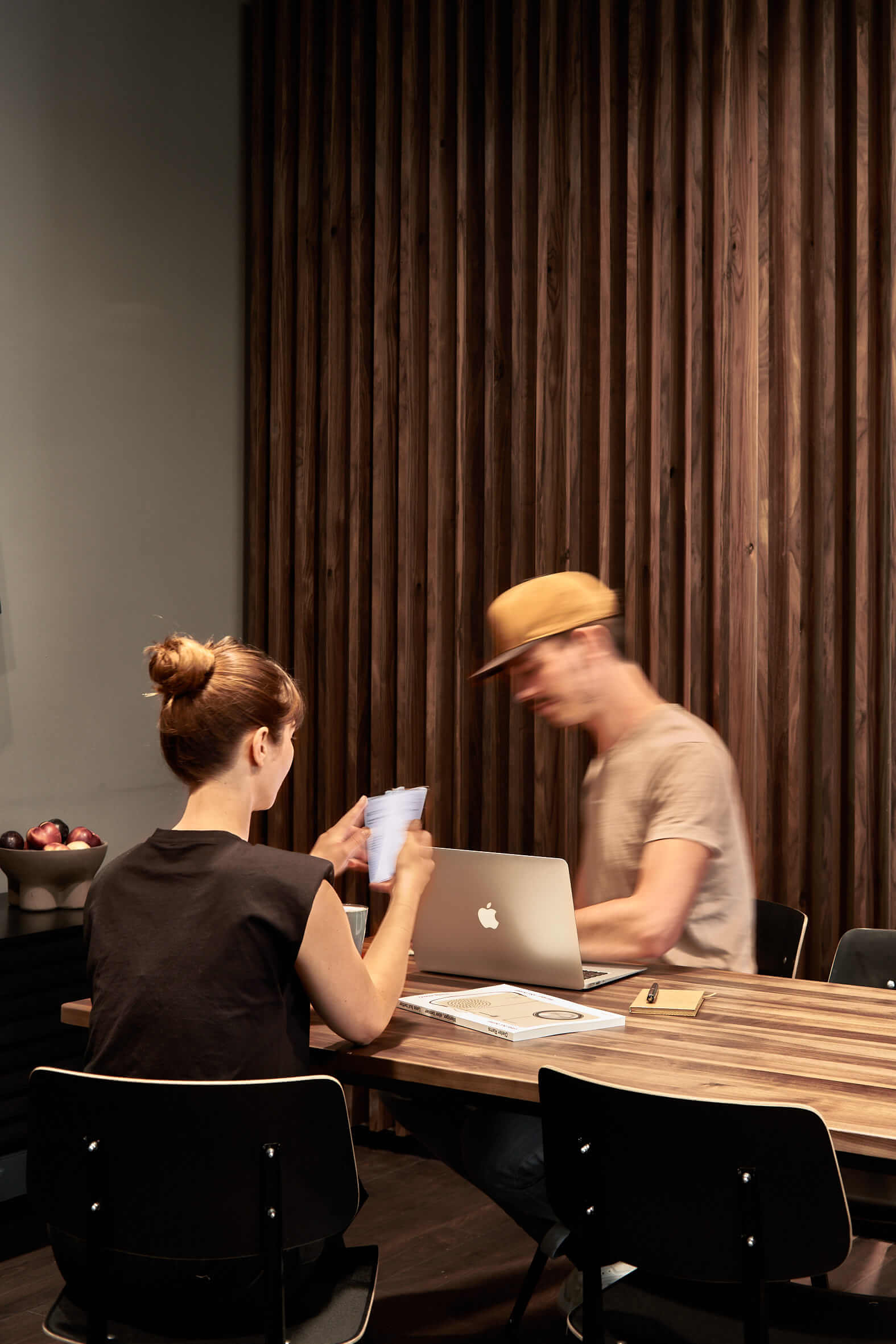 Gelegenheiten zum Networking auf dem Bold Campus nutzen Ein junger Mann und eine Frau sitzen mit einem Laptop und weiterem Arbeitsmaterial an einem Holztisch, hinter den beiden befindet sich ein Sichtschutz aus dunklem Holz.
