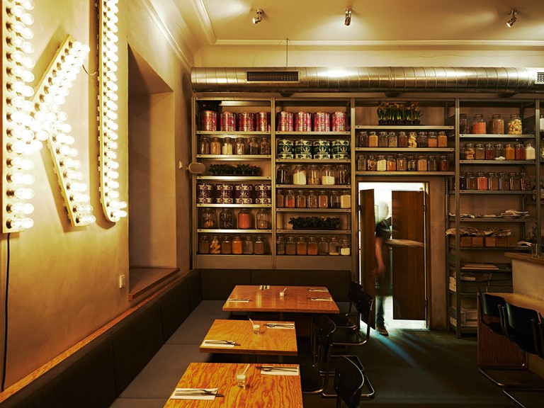 A cosy corner in a restaurant. On the wall are shelves with various ingredients.