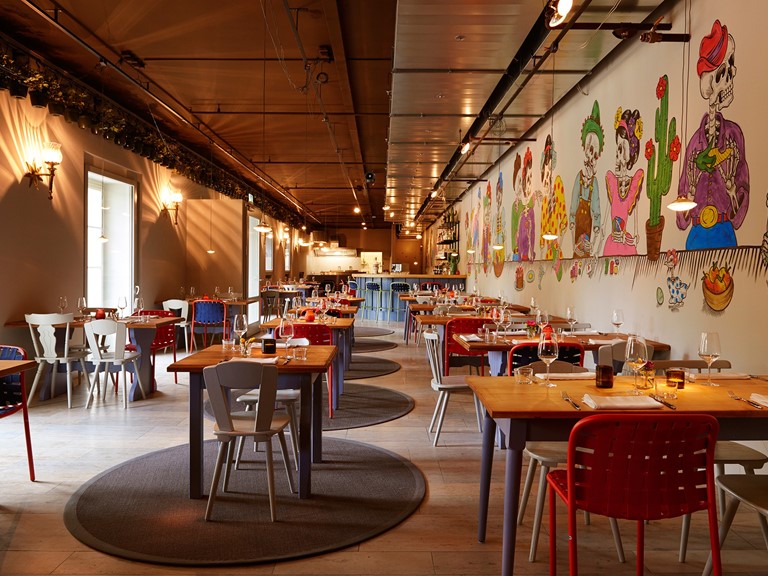 A restaurant with colourful furniture and wallpaper that embodies the diversity of Latin America.