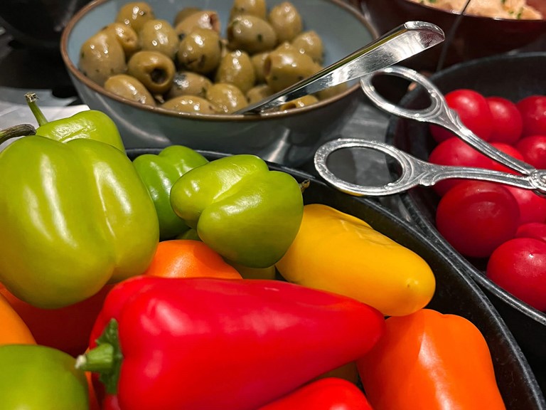 Peppers, tomatoes, olives and spreads in bowls at the buffet.
